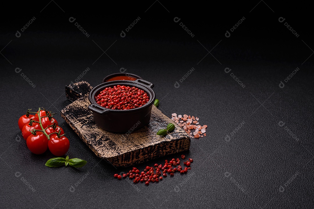 Especiarias, ervilhas de pimenta da Jamaica na cor vermelha ou rosa em uma tigela sobre um fundo preto de concreto. Cozinha asiática