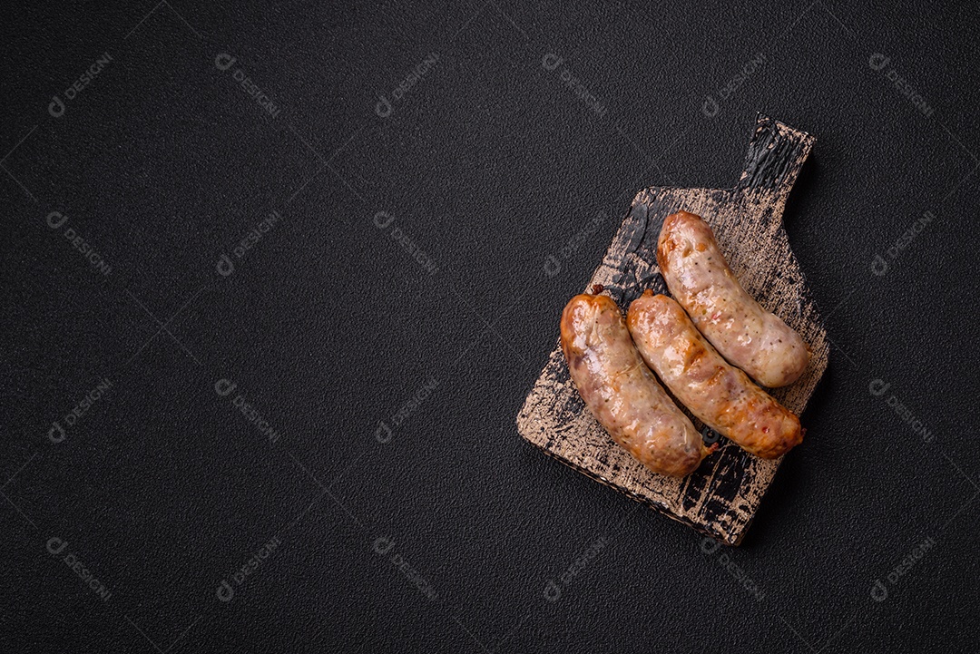 Frango assado ou salsichas de porco, sal, especiarias e ervas sobre um fundo escuro de concreto