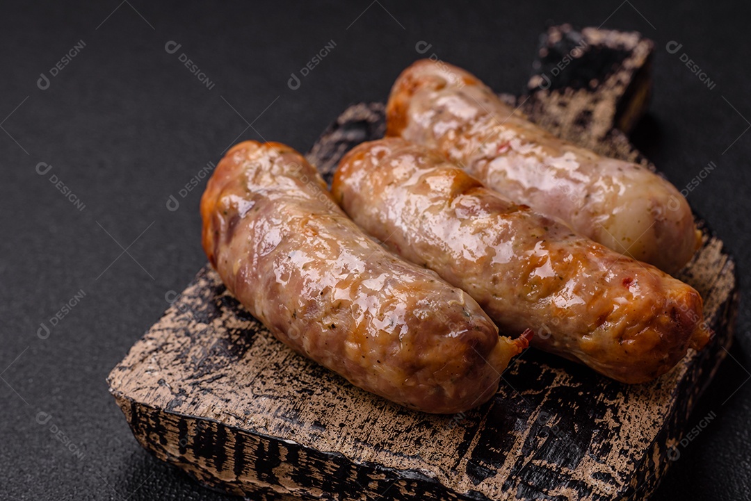 Frango assado ou salsichas de porco, sal, especiarias e ervas sobre um fundo escuro de concreto