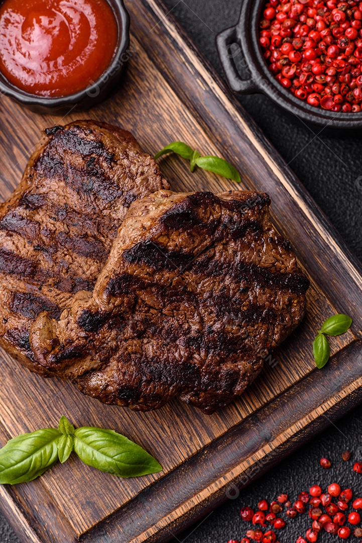 Bife fresco, suculento e delicioso em um fundo escuro. Prato de carne com especiarias e ervas