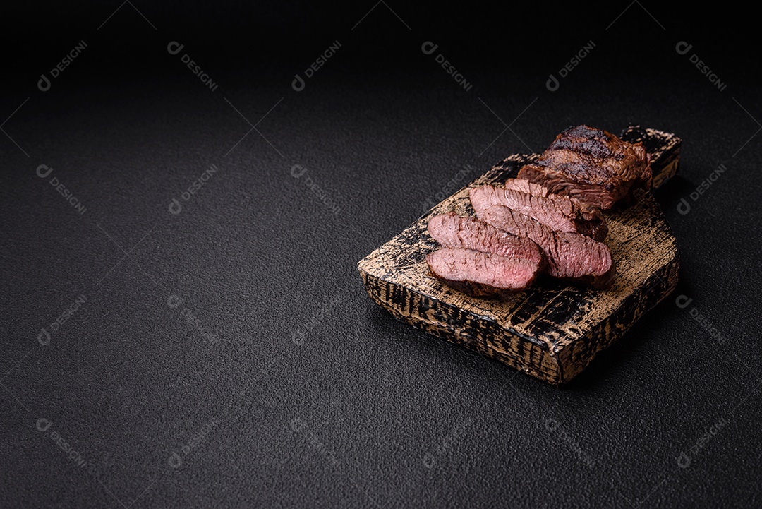 Bife fresco, suculento e delicioso em um fundo escuro. Prato de carne com especiarias e ervas