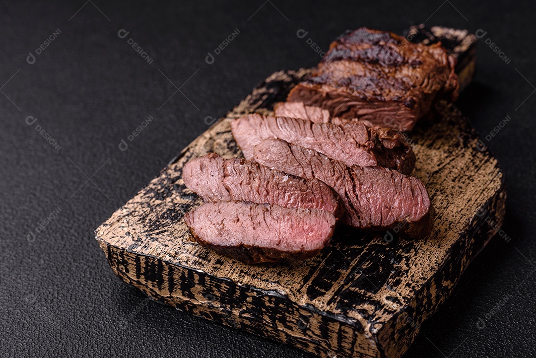 Bife fresco, suculento e delicioso em um fundo escuro. Prato de carne com especiarias e ervas