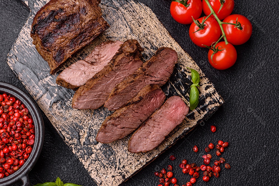 Bife suculento de tomahawk com osso assado na grelha com sal e especiarias em um fundo escuro de concreto