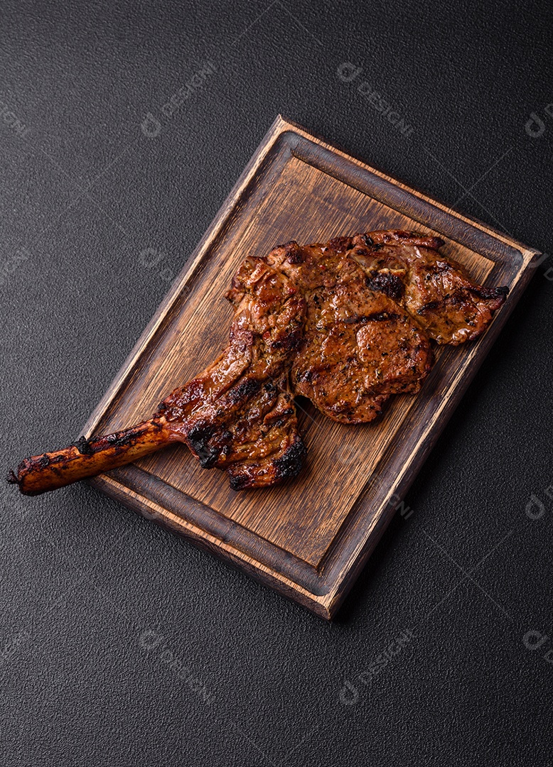 Bife suculento de tomahawk com osso assado na grelha com sal e especiarias em um fundo escuro de concreto