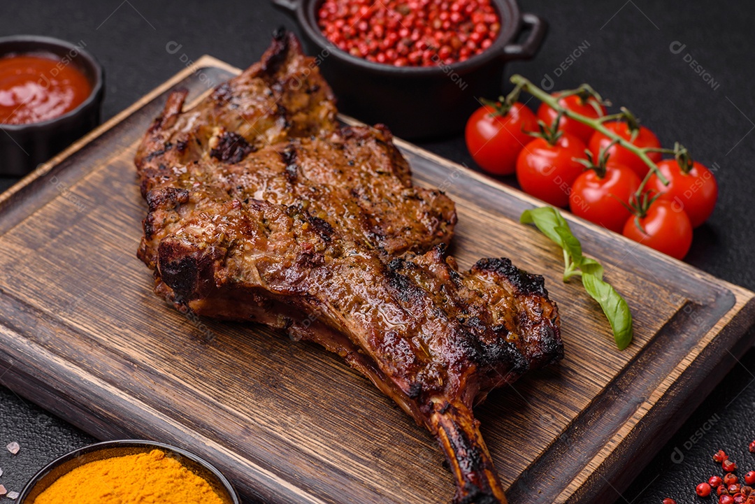 Bife suculento de tomahawk com osso assado na grelha com sal e especiarias em um fundo escuro de concreto