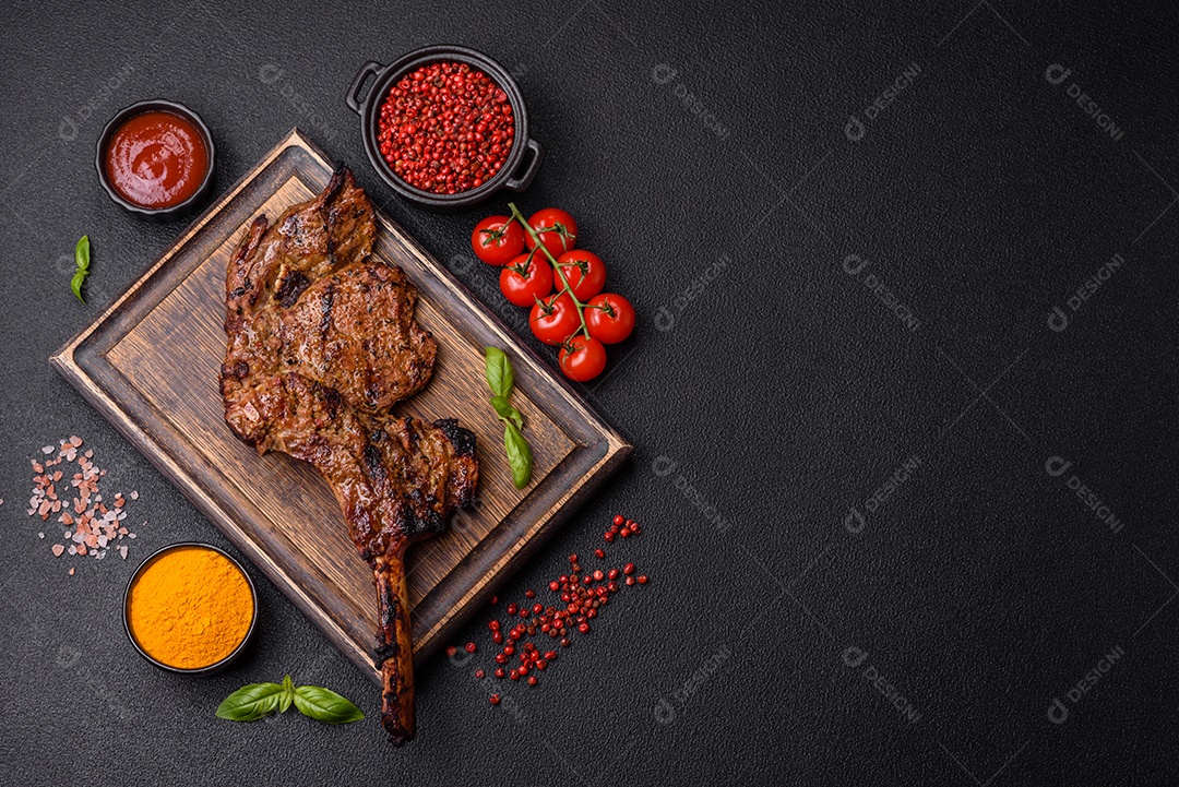 Bife suculento de tomahawk com osso assado na grelha com sal e especiarias em um fundo escuro de concreto