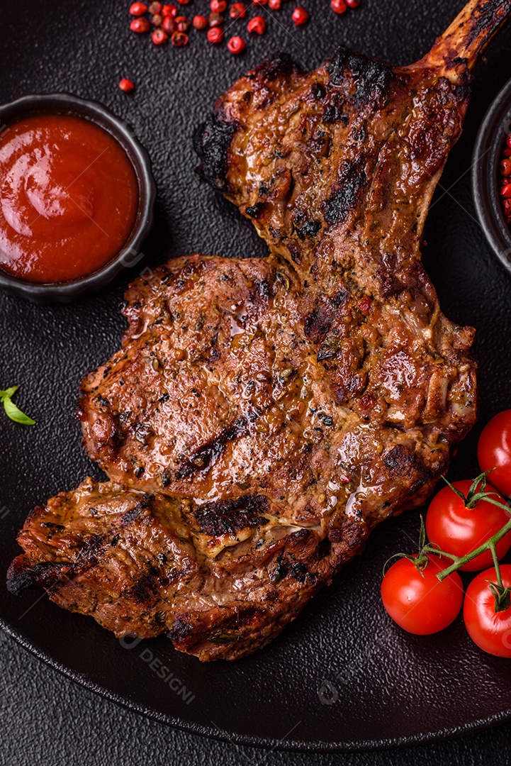 Bife suculento de tomahawk com osso assado na grelha com sal e especiarias em um fundo escuro de concreto