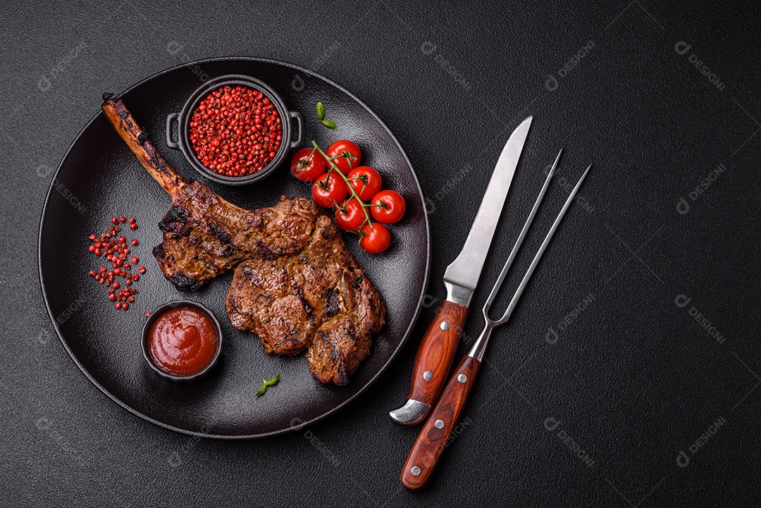 Bife suculento de tomahawk com osso assado na grelha com sal e especiarias em um fundo escuro de concreto