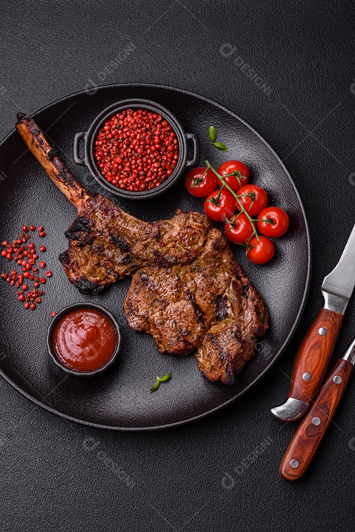 Bife suculento de tomahawk com osso assado na grelha com sal e especiarias em um fundo escuro de concreto