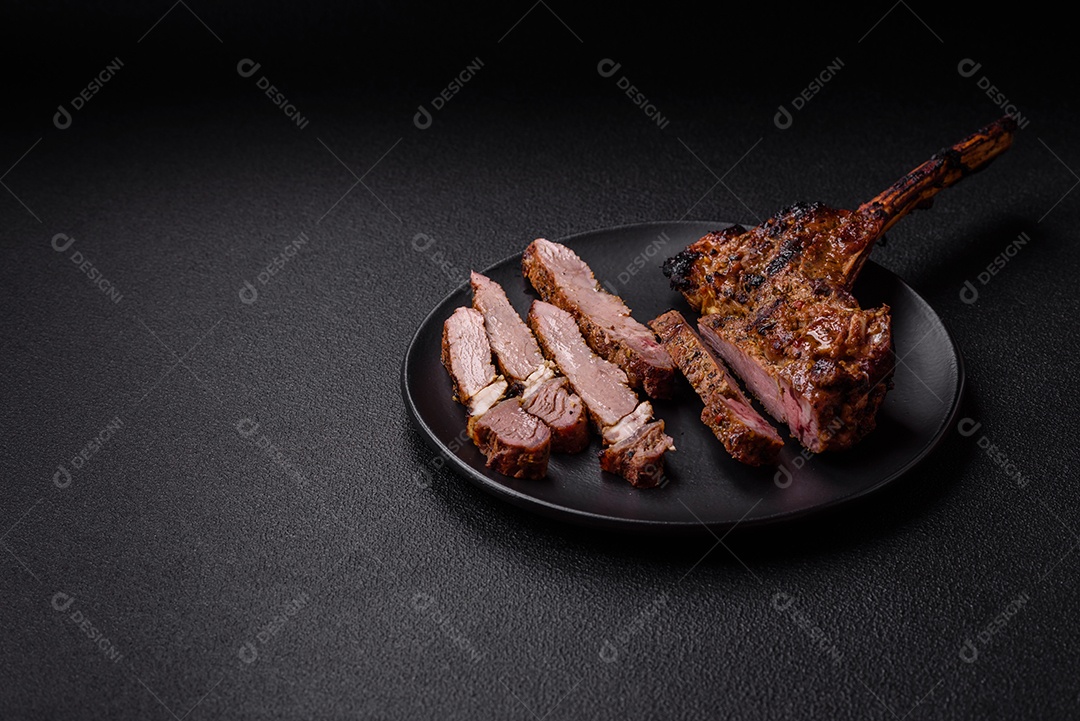 Bife suculento de tomahawk com osso assado na grelha com sal e especiarias em um fundo escuro de concreto