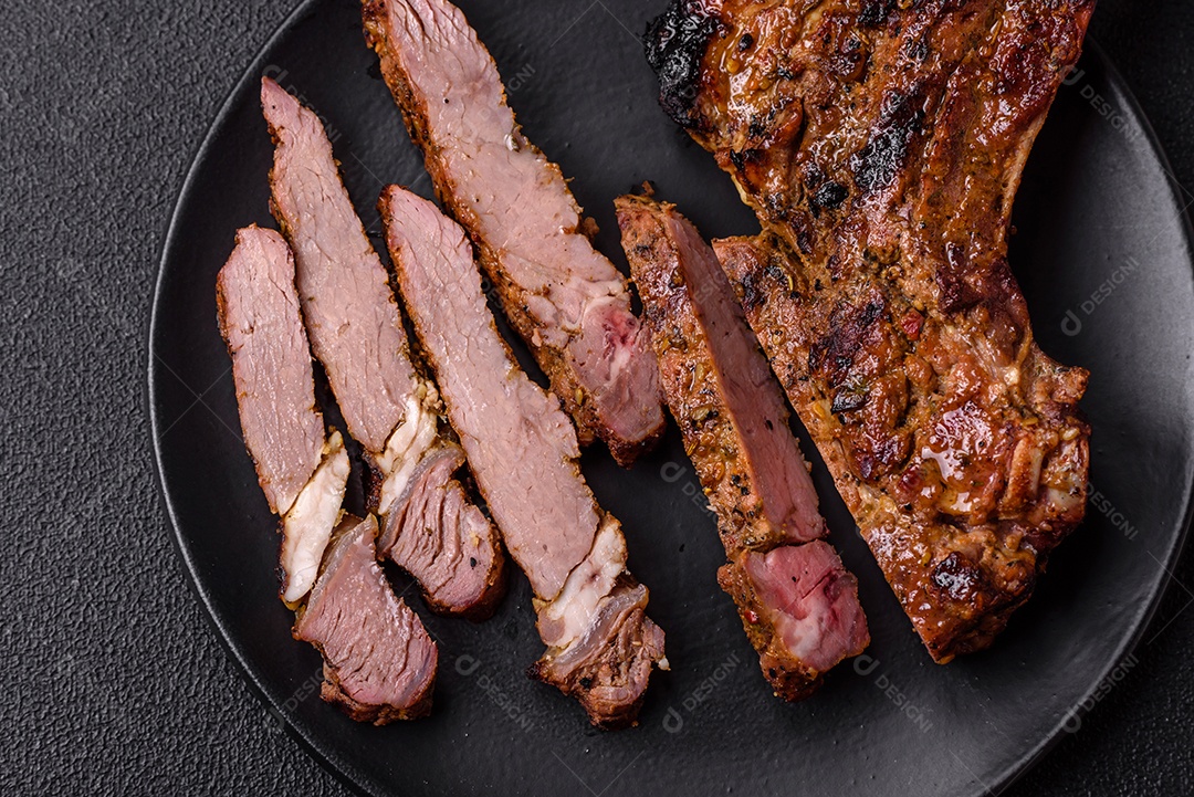 Bife suculento de tomahawk com osso assado na grelha com sal e especiarias em um fundo escuro de concreto