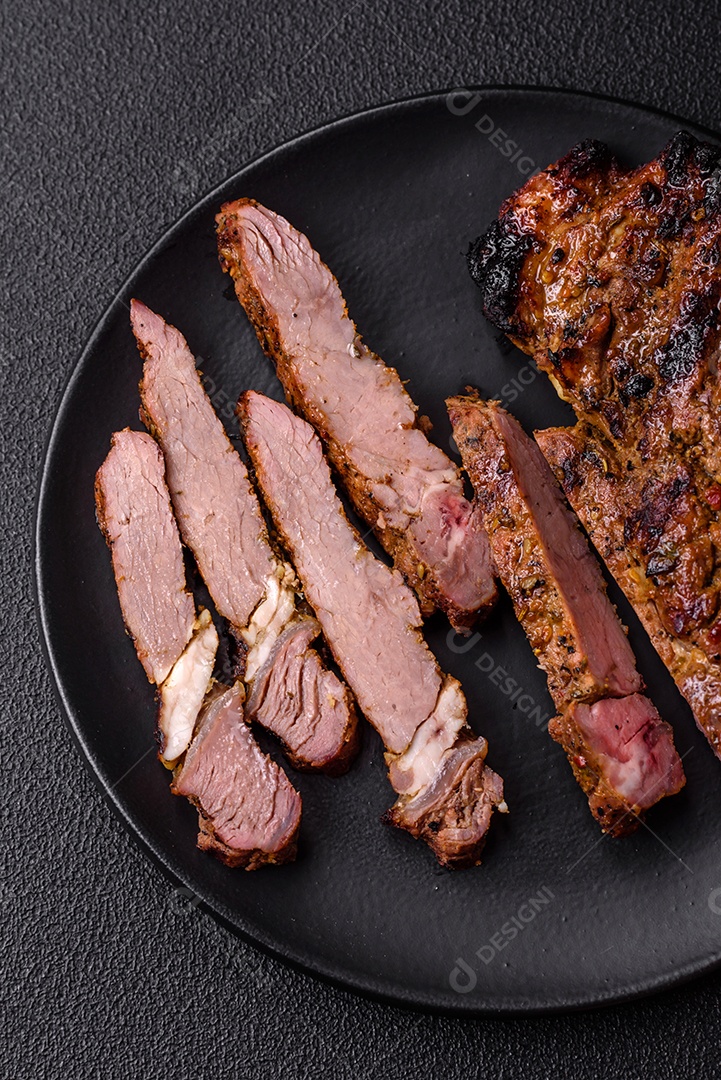 Bife suculento de tomahawk com osso assado na grelha com sal e especiarias em um fundo escuro de concreto