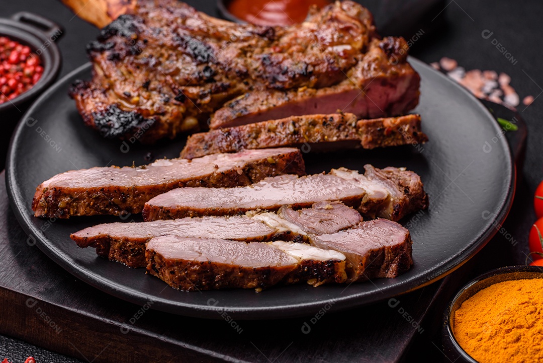 Bife suculento de tomahawk com osso assado na grelha com sal e especiarias em um fundo escuro de concreto
