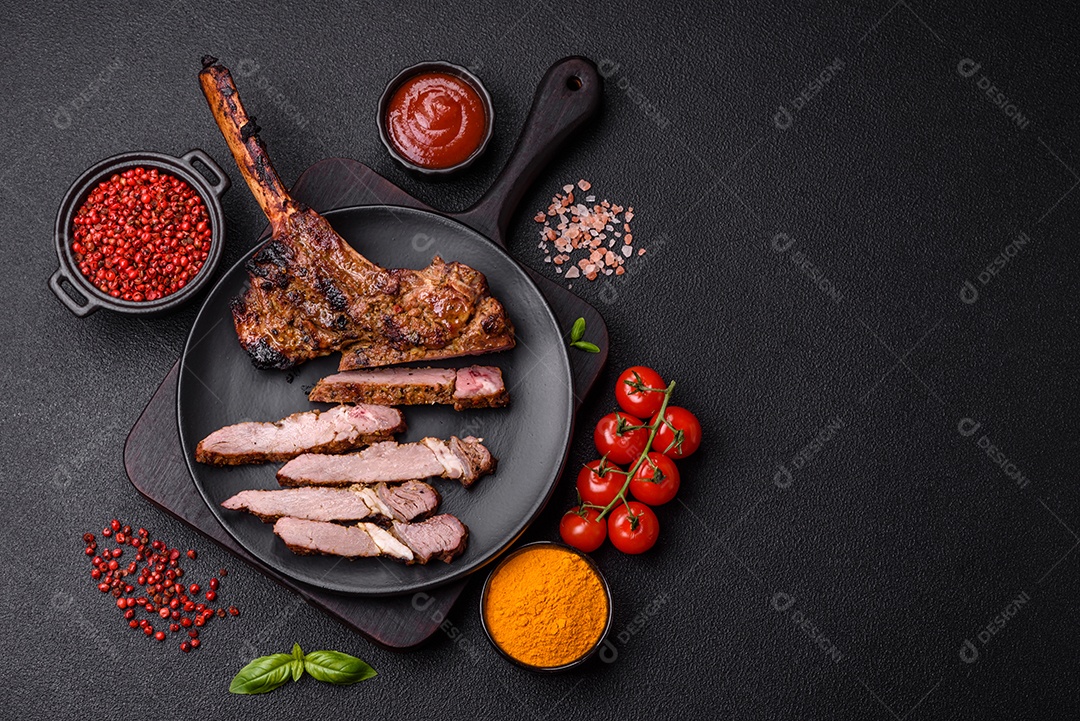 Bife suculento de tomahawk com osso assado na grelha com sal e especiarias em um fundo escuro de concreto