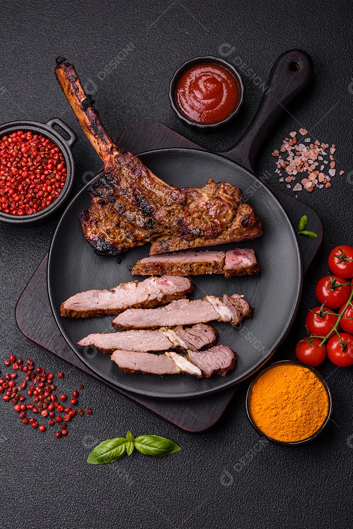 Bife suculento de tomahawk com osso assado na grelha com sal e especiarias em um fundo escuro de concreto