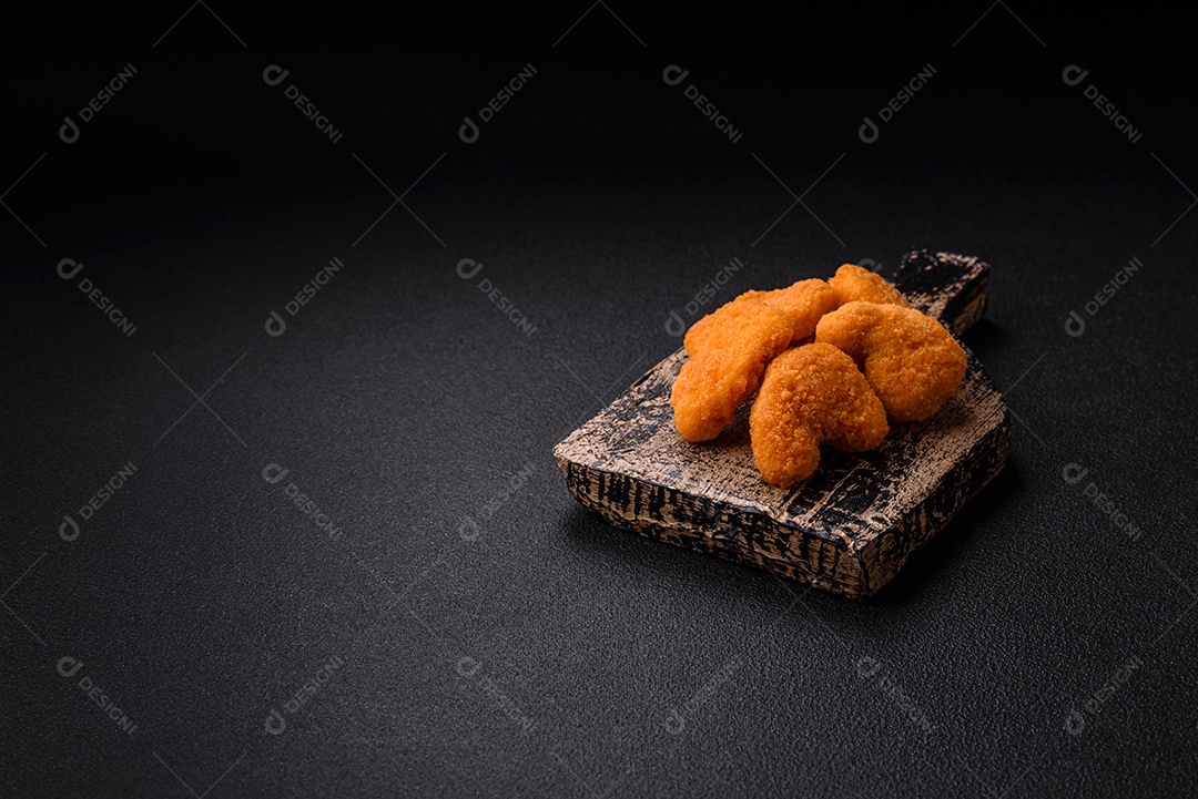 Deliciosos nuggets de frango crocantes frescos em um fundo escuro de concreto. Alimentos não saudáveis, fast food