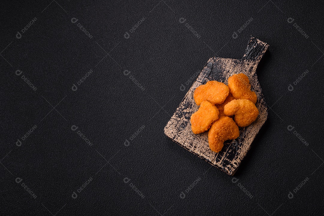 Deliciosos nuggets de frango crocantes frescos em um fundo escuro de concreto. Alimentos não saudáveis, fast food