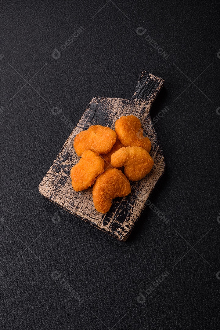 Deliciosos nuggets de frango crocantes frescos em um fundo escuro de concreto. Alimentos não saudáveis, fast food