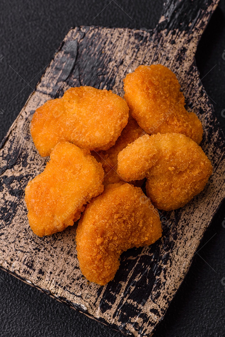 Deliciosos nuggets de frango crocantes frescos em um fundo escuro de concreto. Alimentos não saudáveis, fast food