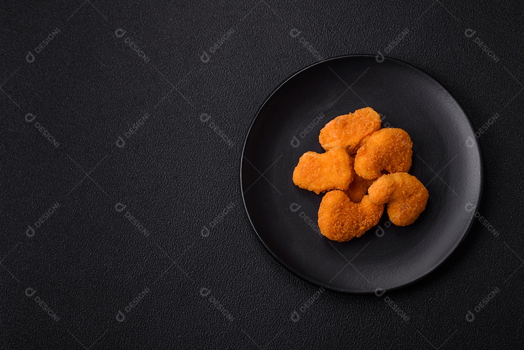 Deliciosos nuggets de frango crocantes frescos em um fundo escuro de concreto. Alimentos não saudáveis, fast food