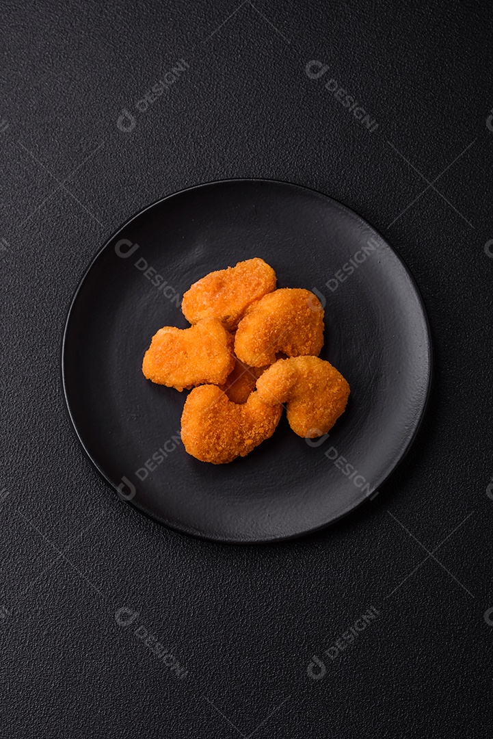 Deliciosos nuggets de frango crocantes frescos em um fundo escuro de concreto. Alimentos não saudáveis, fast food