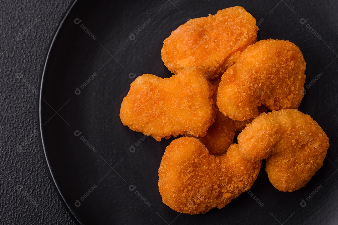 Deliciosos nuggets de frango crocantes frescos em um fundo escuro de concreto. Alimentos não saudáveis, fast food