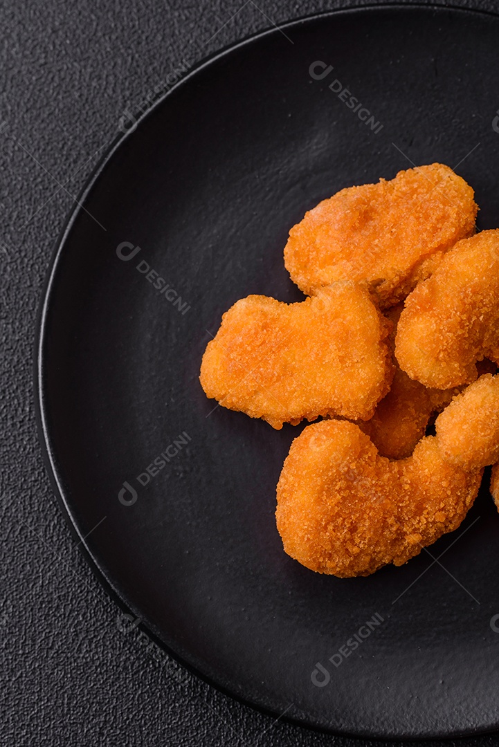 Deliciosos nuggets de frango crocantes frescos em um fundo escuro de concreto. Alimentos não saudáveis, fast food