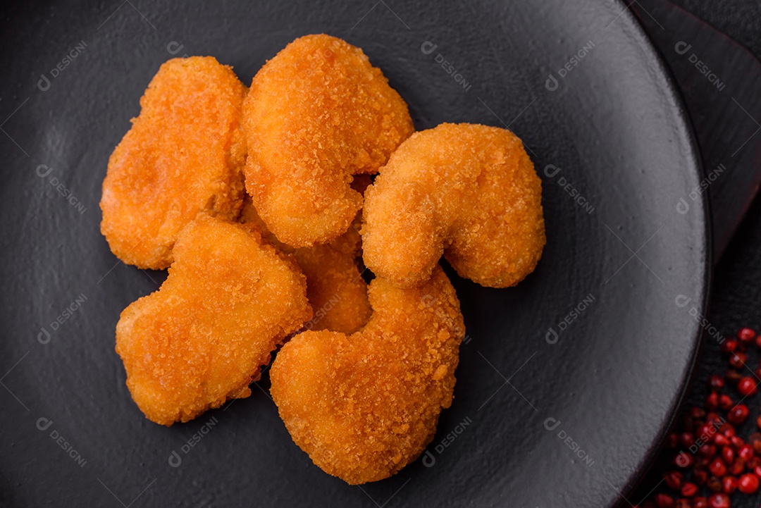Deliciosos nuggets de frango crocantes frescos em um fundo escuro de concreto. Alimentos não saudáveis, fast food