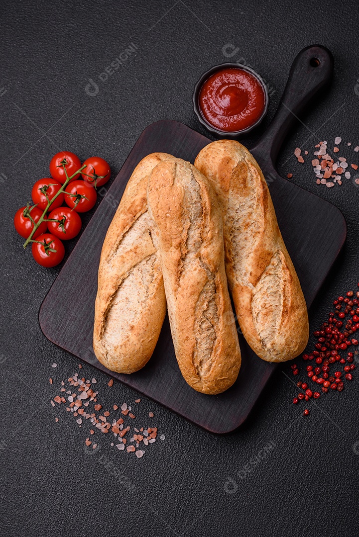 Mini baguete crocante com sementes e grãos, sal e especiarias sobre fundo escuro de concreto