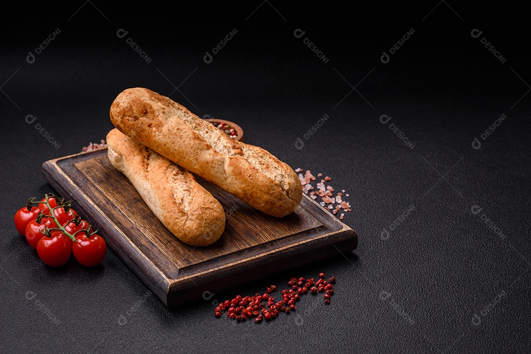 Mini baguete crocante com sementes e grãos, sal e especiarias sobre fundo escuro de concreto