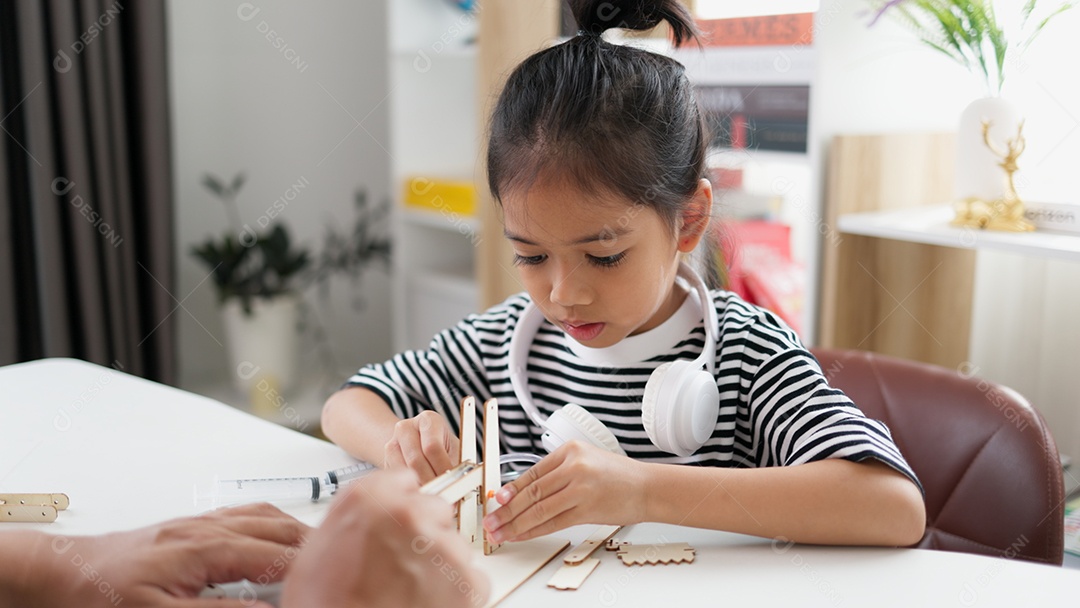 Garotinha asiática concentrada montando torre de madeira