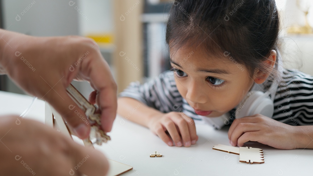 Pai ajudando sua filha na montagem de um objeto