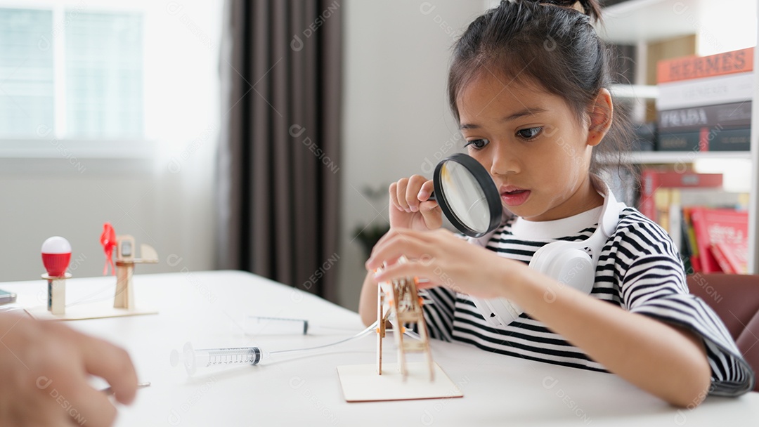 Garotinha olhando por lupa para montar seu objeto