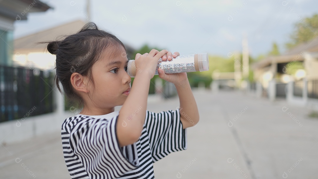 Criança feliz olhando para frente por um binoculo