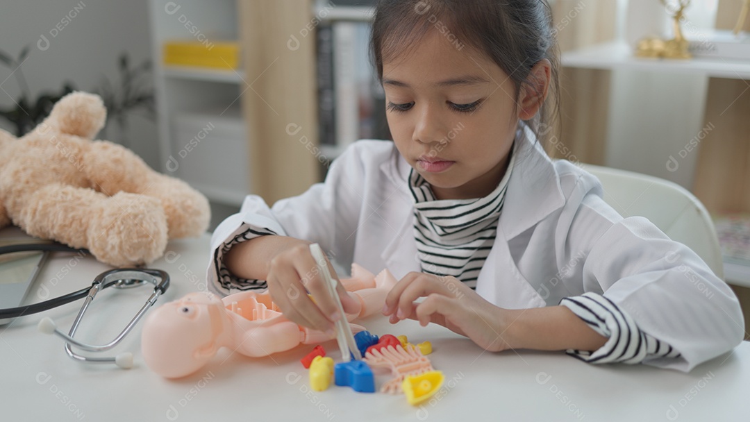 Garotinha asiática brincando com boneco anatômico