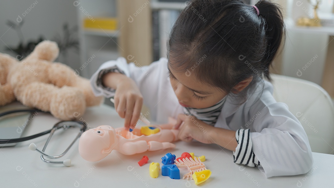 Garotinha asiática brincando com boneco anatômico