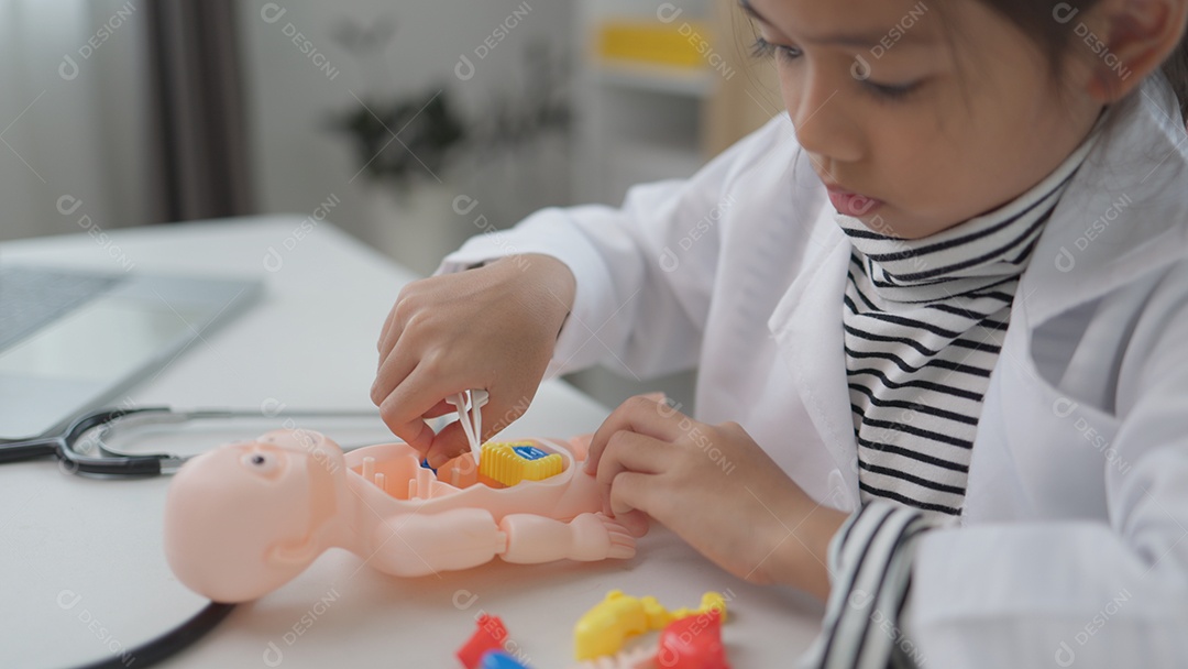 Garotinha asiática brincando com boneco anatômico