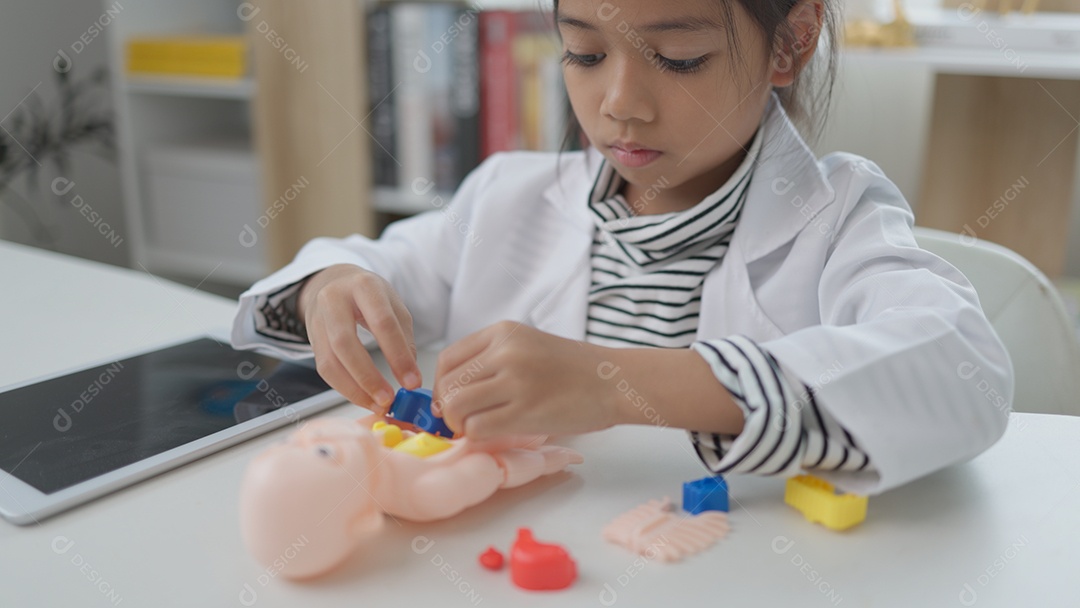 Garotinha asiática brincando com boneco anatômico