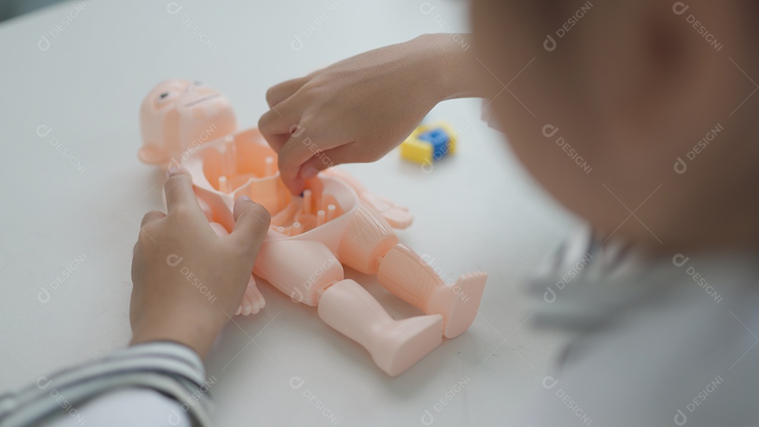 Menina asiática brincando com bonecos anatômicos em um jogo de médico