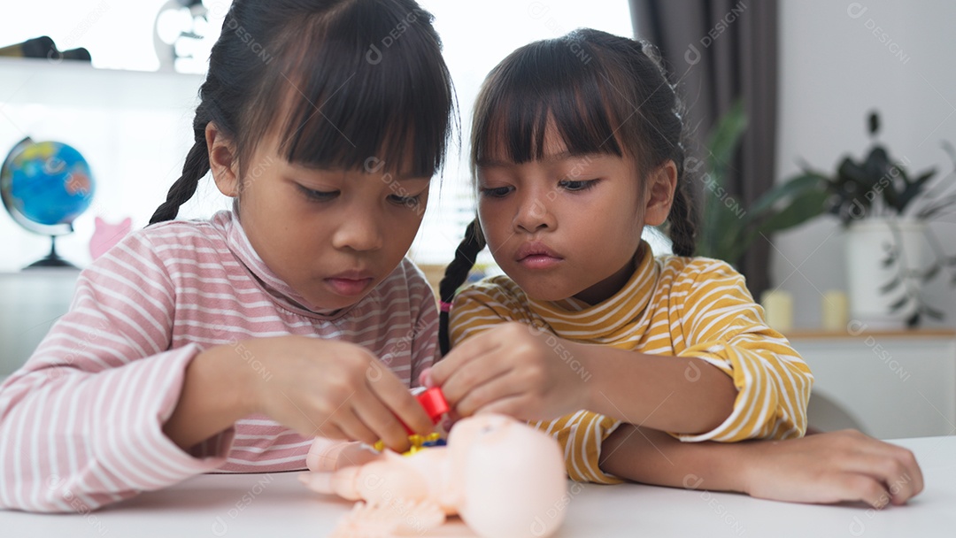 Duas meninas asiáticas montando brinquedo de corpo humano