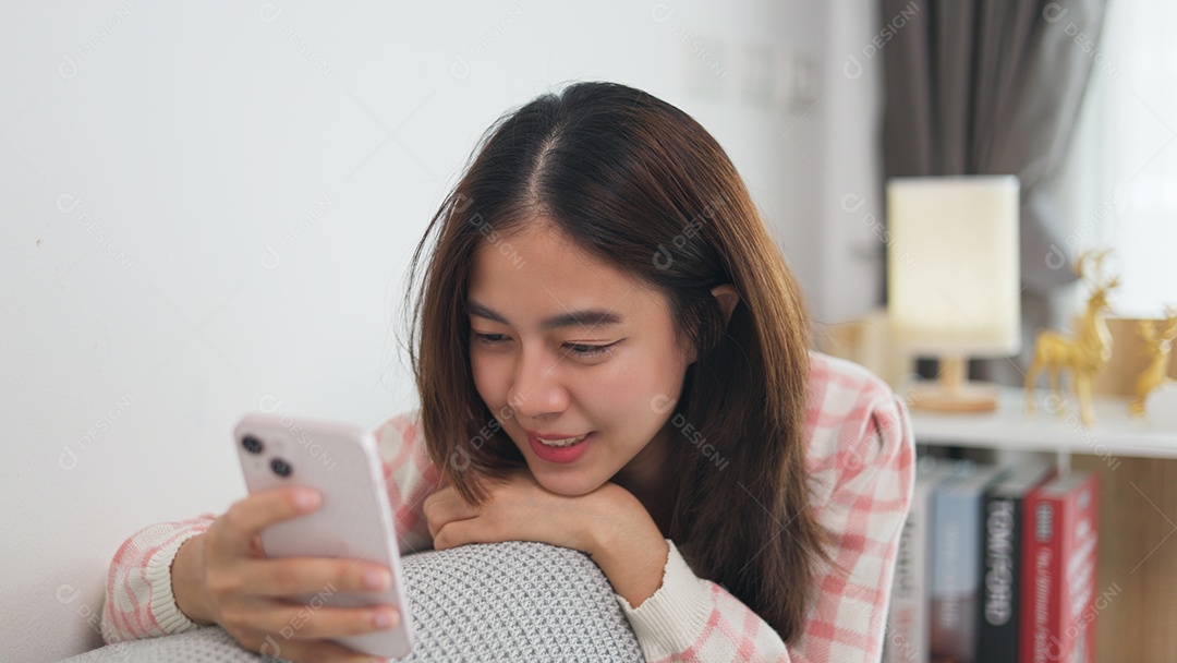 Garota asiática mexendo no celular e sorrindo