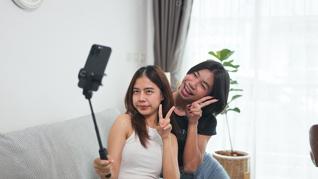 Garota e amiga LGBTQ estão sentadas em um sofá aconchegante tirando uma selfie