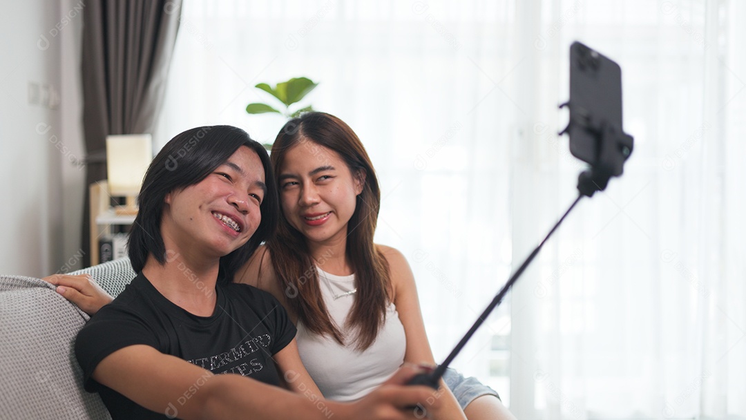 Garota e amiga LGBTQ estão sentadas em um sofá aconchegante tirando uma selfie