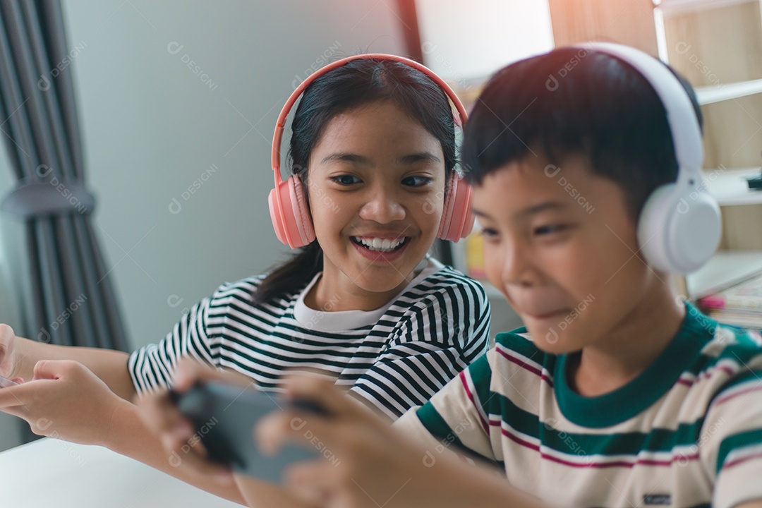 Crianças asiáticas jogam videogame online com amigos em celulares para se divertir