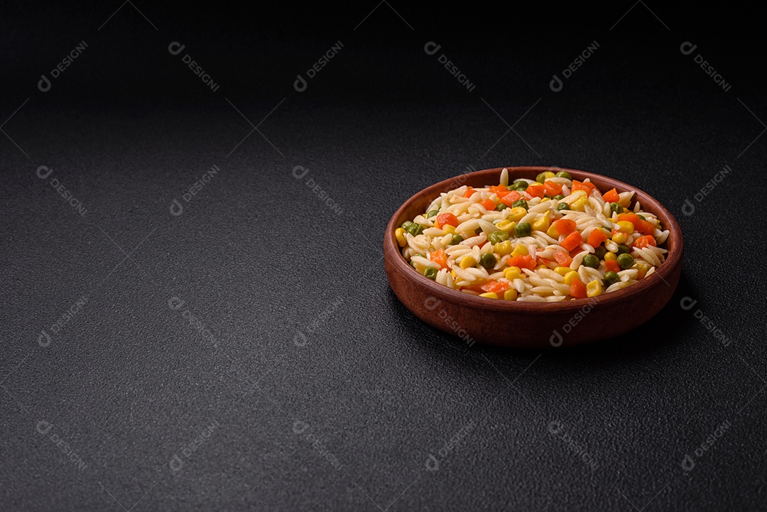 Delicioso arroz cozido com legumes milho, cenouras, ervilhas com sal, especiarias e ervas sobre um fundo escuro de concreto