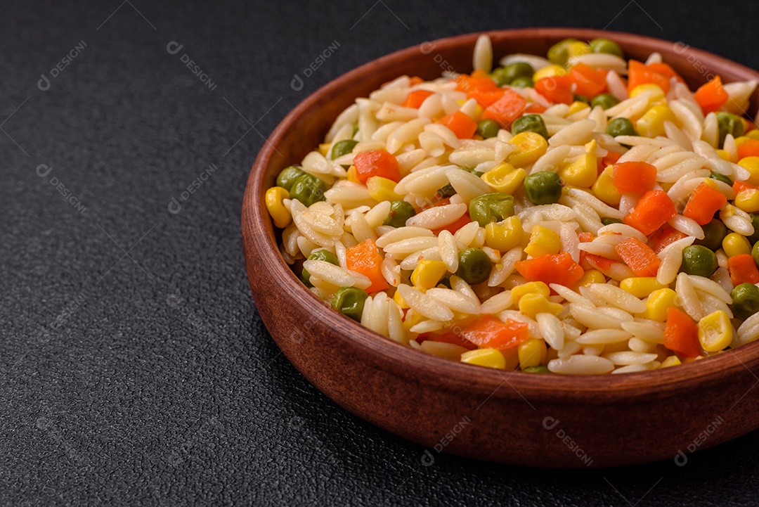 Delicioso arroz cozido com legumes milho, cenouras, ervilhas com sal, especiarias e ervas sobre um fundo escuro de concreto