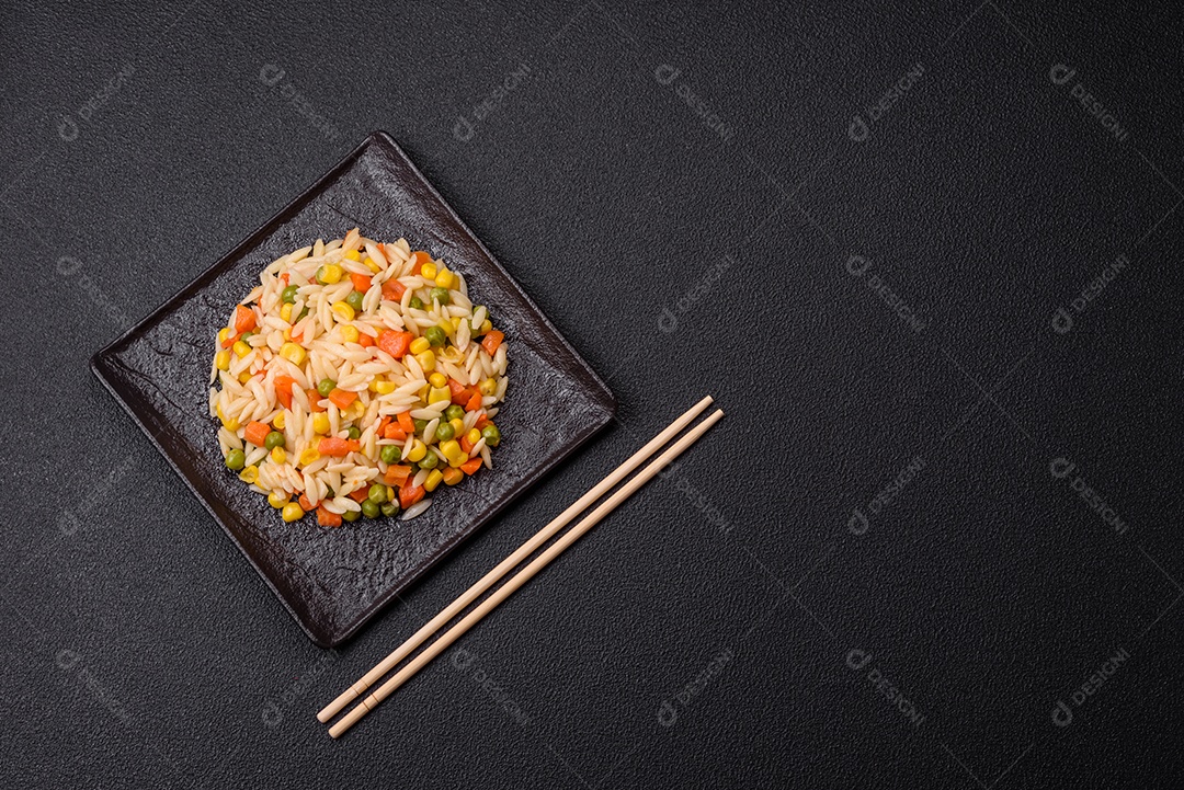 Delicioso arroz cozido com legumes milho, cenouras, ervilhas com sal, especiarias e ervas sobre um fundo escuro de concreto