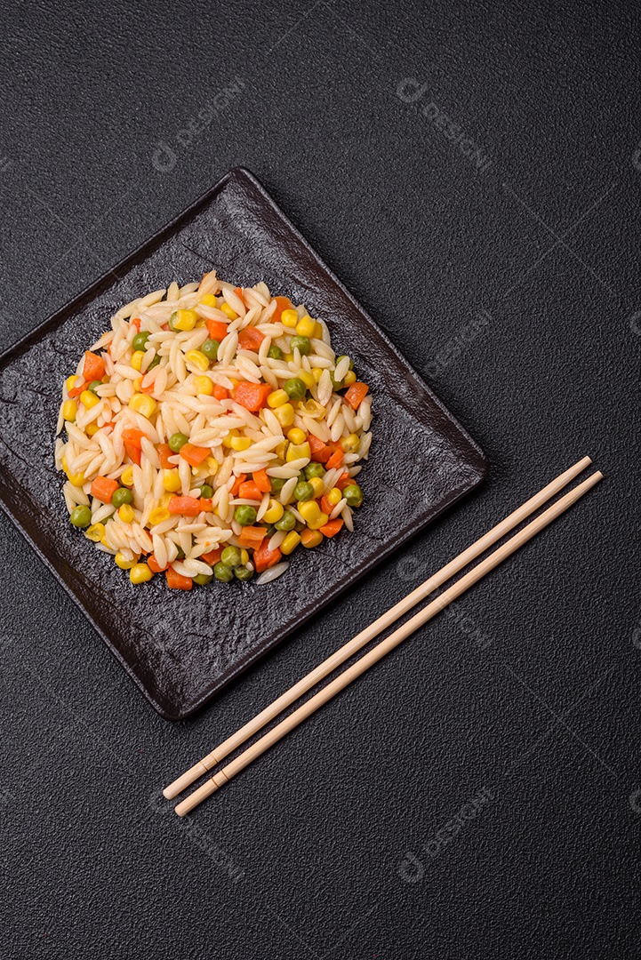 Delicioso arroz cozido com legumes milho, cenouras, ervilhas com sal, especiarias e ervas sobre um fundo escuro de concreto