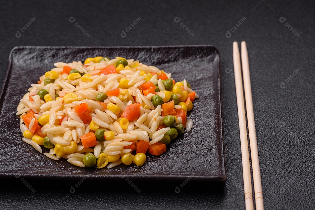 Delicioso arroz cozido com legumes milho, cenouras, ervilhas com sal, especiarias e ervas sobre um fundo escuro de concreto
