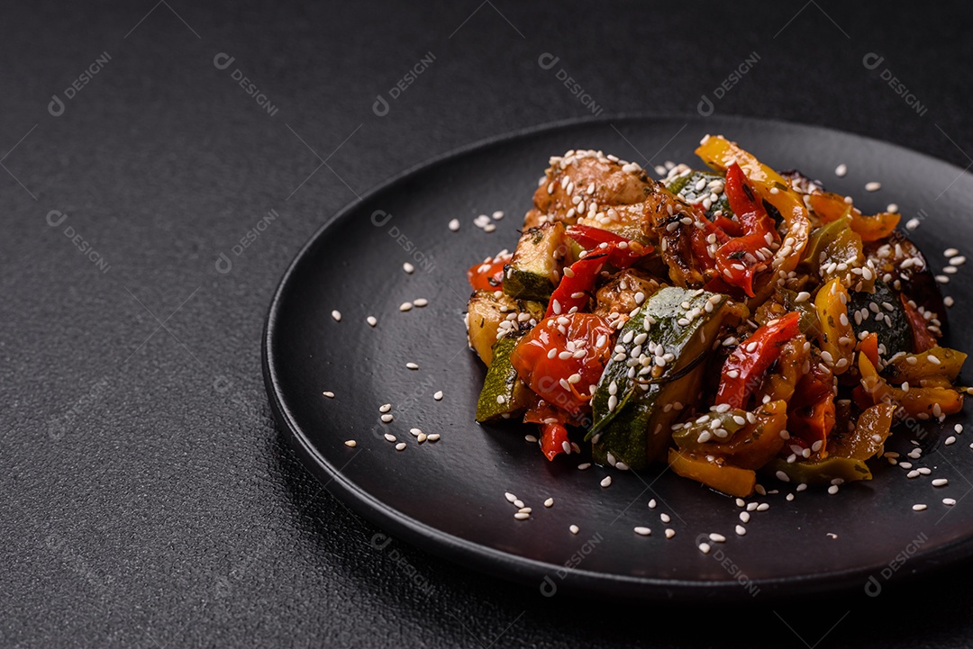 Prato asiático picante com filé de carne fatiado, pimenta, cenoura e sementes de gergelim sobre um fundo escuro de concreto